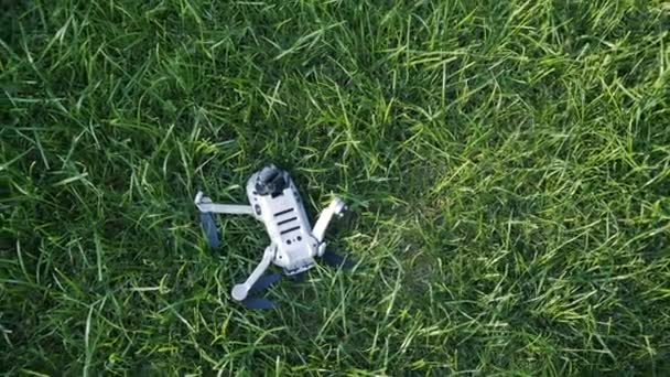 Moderne kleine drone neergestort in groen gras — Stockvideo