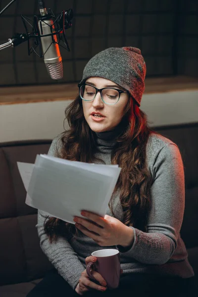 Woman preparing material before radio show, studio recording. Soundproof room for professional recording vocal. Voice artist works with material of some broadcast live show. Dubbing