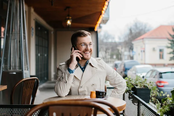 Νεαρός Πίνει Καφέ Και Μιλάει Στο Τηλέφωνο Ένα Υπαίθριο Καφέ — Φωτογραφία Αρχείου