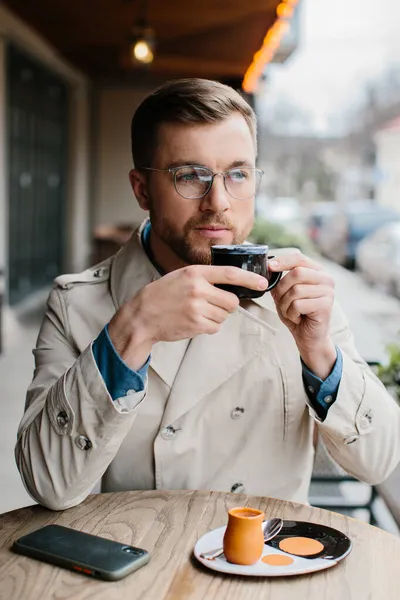 若い男が屋外カフェでコーヒーを飲む — ストック写真
