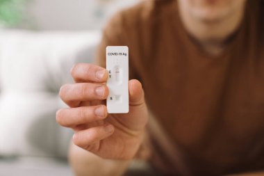 Genç adam evdeki kanepede otururken kovid 19 testini kontrol ediyor..