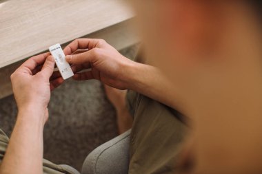 Genç adam evdeki kanepede otururken kovid 19 testini kontrol ediyor..