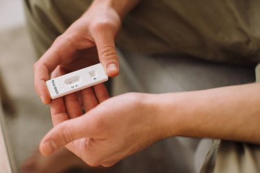 Genç adam evdeki kanepede otururken kovid 19 testini kontrol ediyor..