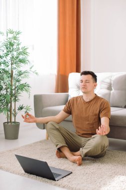 Evde dizüstü bilgisayar başında egzersiz yapan bir adam.