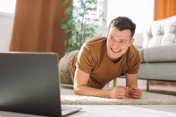 家でノートパソコンでチュートリアルを見ながら運動する男 — ストック写真