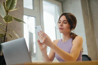Girl uses laptop for remote work or home leisure while sitting in the kitchen at home.