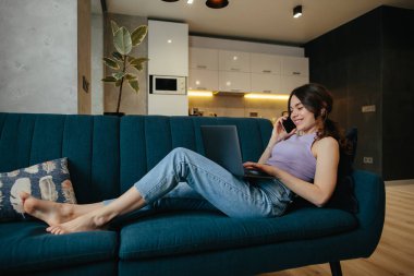 Girl uses laptop for remote work or home leisure while sitting in the kitchen at home.