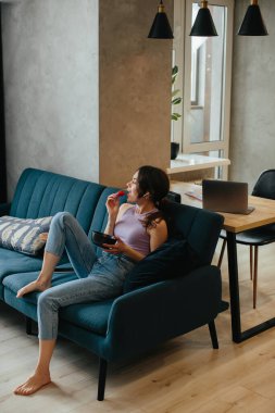 Young girl sitting on the couch and eating strawberrie