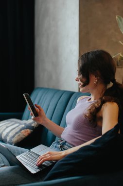 Girl uses laptop for remote work or home leisure while sitting in the kitchen at home.