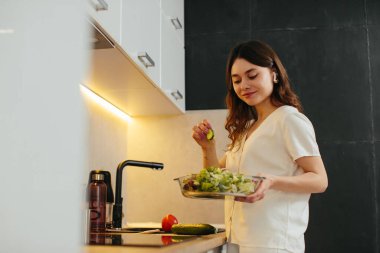 Young woman preparing salad in kitchen, stock phot