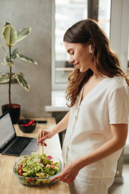 Young woman preparing salad in kitchen, stock phot