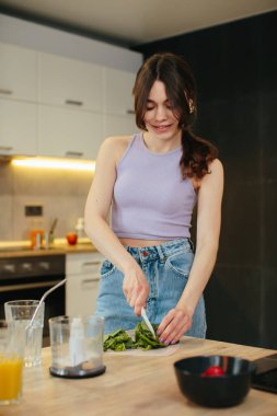 Genç bayan mutfakta sağlıklı yeşil smoothie hazırlıyor.