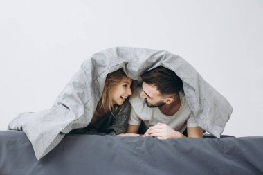 Mutlu çift battaniyenin altında eğleniyor.