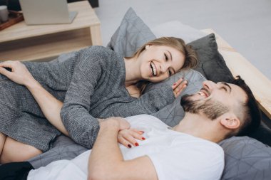 Genç ve mutlu bir çift yatak odasında birlikte eğleniyor.