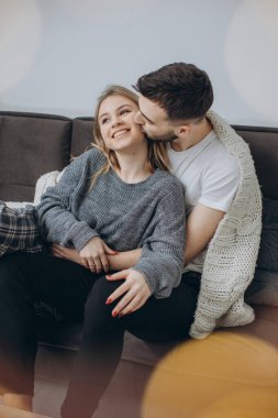 Couple in love sitting on the couch in the living room, wearing pajamas after getting up in the morning, enjoying the morning and having breakfast clipart