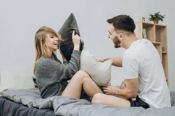ベッドの中で戦う枕を持っている幸せな愛情のあるカップルの肖像画 — ストック写真