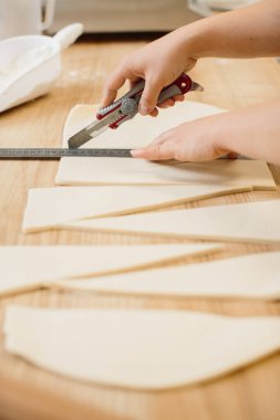 Kadın fırıncı kruvasan için hamuru üçgen şeklinde keser. Fırında kruvasan yapıyorum..