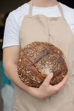 Kadın fırıncının elinde taze ekmek tutarken yakın plan..