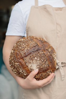 Kadın fırıncının elinde taze ekmek tutarken yakın plan..