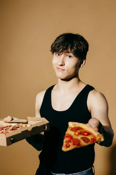 Young man with pizza on a colored background.