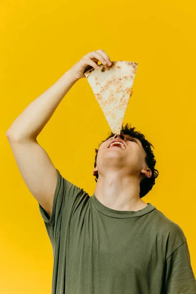 Egy Fiatalember Eszik Egy Szelet Pizzát Stúdió Fotó Színes Háttér — Stock Fotó