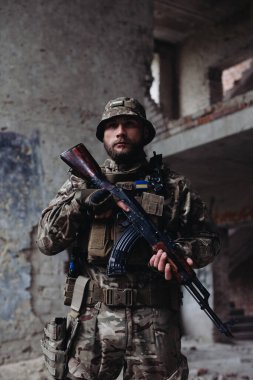 Bir Ukraynalı asker yıkılmış binaların arkasında poz veriyor. Ukrayna ve Rusya arasındaki savaş