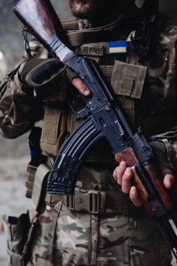 Bir asker bir saldırı tüfeği tutuyor, yakın plan..