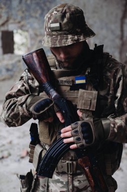 Bir Ukraynalı asker yıkılmış binaların arkasında poz veriyor. Ukrayna ve Rusya arasındaki savaş