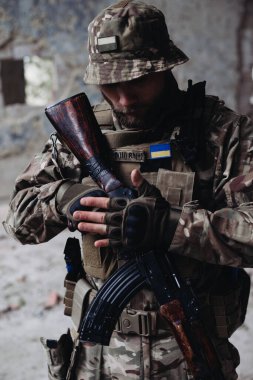 Bir Ukraynalı asker yıkılmış binaların arkasında poz veriyor. Ukrayna ve Rusya arasındaki savaş