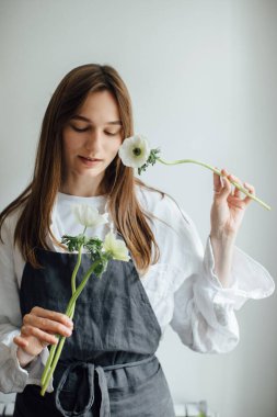 Genç bir çiçekçi kız çiçek düzenliyor..