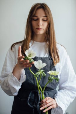 Genç bir çiçekçi kız çiçek düzenliyor..