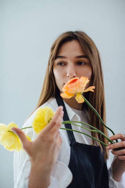 Woman smelling flowers while arranging it at flower shop - stock phot