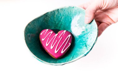 Beyaz arka planda ev yapımı seramik bir turkuazda kalp şeklinde zencefilli çörek.