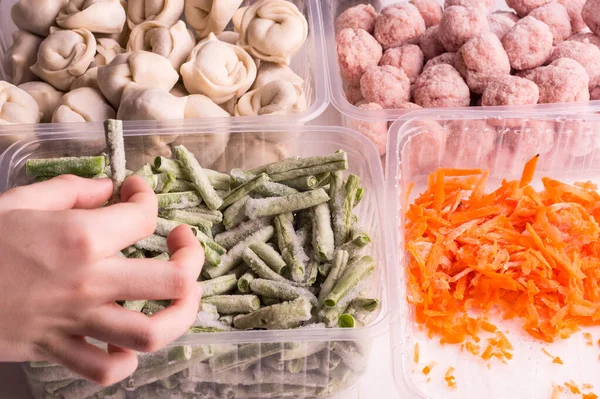 Containers with frozen  vegetables and semi-finished meat products  from the refrigerator. meatballs, dumplings, chopped beans and grated carrots