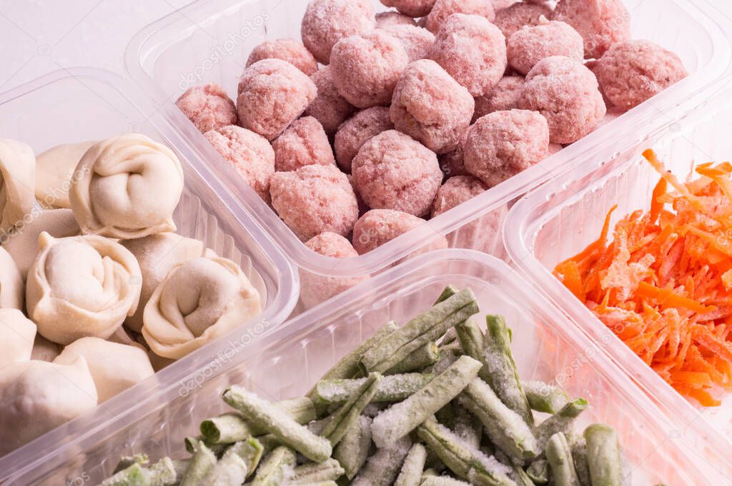 Containers with frozen  vegetables and semi-finished meat products  from the refrigerator. meatballs, dumplings,  chopped beans and grated carrots