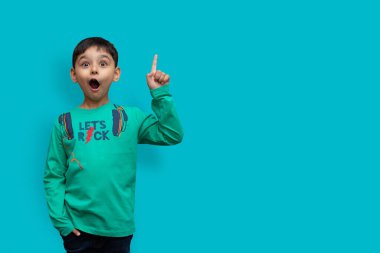 Vay canına, buraya reklam verin! Şaşkın küçük çocuğun portresi arka plandaki boş yeri işaret ediyor, şaşırmış okul çocuğunun fotokopi alanı göstermesi