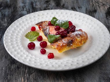 Böğürtlen soslu süzme peynir güveci ve beyaz tabakta donmuş kızılcık.