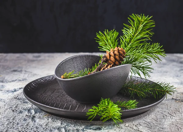 Siyah tabaklarda köknar dalları ve koniler bulunan masa dekorasyonu için yeni yıl kompozisyonu — Stok fotoğraf