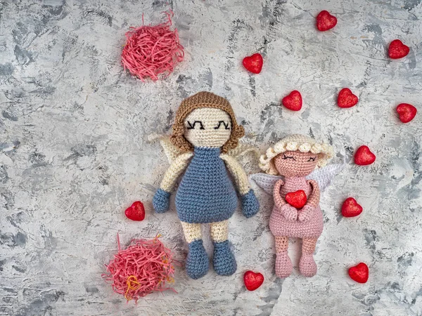 Dos ángeles de ganchillo sosteniendo una paja decorativa con corazones de color rosa, una tarjeta de San Valentín — Foto de Stock