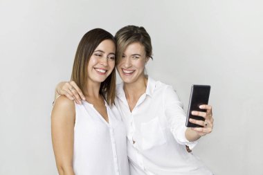 Güzel mutlu ve gülümseyen bayan arkadaş öpücükle selfie çekiyor. Beyazda izole edilmiş