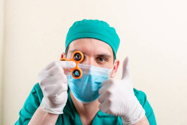 Elinde fırıldak olan maske ve eldivenli bir doktor..