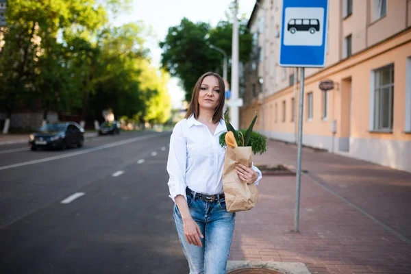 漂亮的女孩和一个纸袋与食品杂货 高质量的照片 — 图库照片