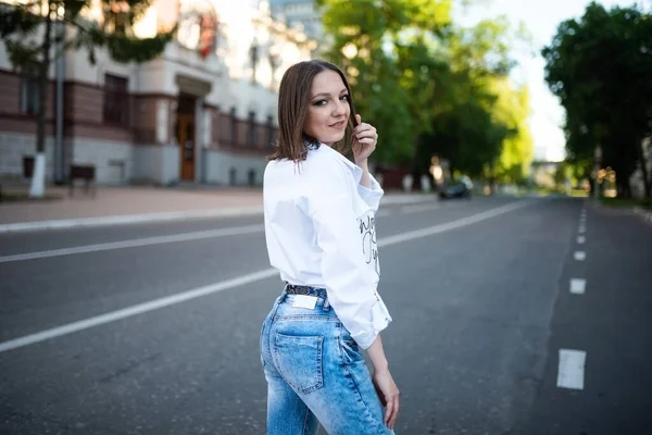 Vacker flicka i jeans och en vit blus. — Stockfoto