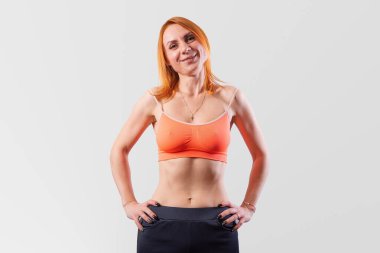 Beautiful girl with a short sports top, on a gray background