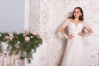 Gelin, güzel bir elbise içinde, beyaz bir duvarın arkasında. Yüksek kalite fotoğraf