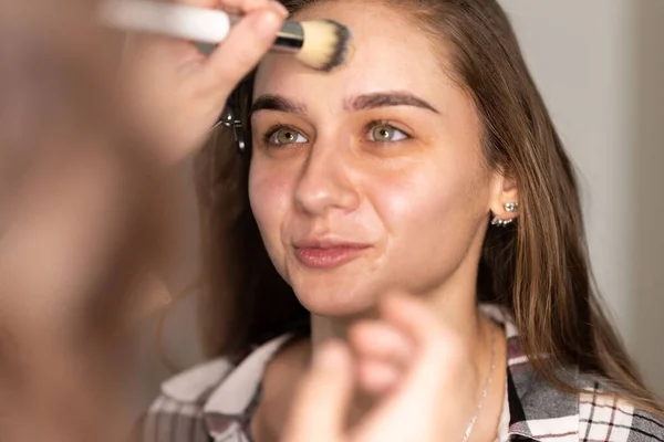 Makeup Καλλιτέχνης Διανέμει Θεμέλια Στο Πρόσωπο Του Κοριτσιού Ένα Πινέλο — Φωτογραφία Αρχείου