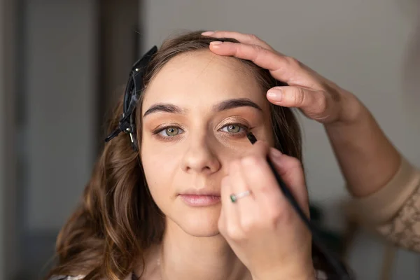 Μακιγιέρ Εφαρμόζει Eyeliner Στο Κορίτσι Ένα Πινέλο Στο Πάνω Βλέφαρο — Φωτογραφία Αρχείου