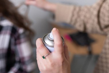 Stilist saç spreyiyle bukleleri düzeltir. Yüksek kalite fotoğraf