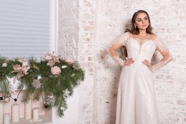 Gelin, güzel bir elbise içinde, beyaz bir duvarın arkasında. Yüksek kalite fotoğraf