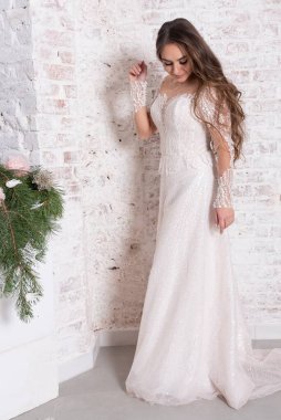 Gelin, beyaz tuğla bir duvarın arka planında, tam gelişim içinde..